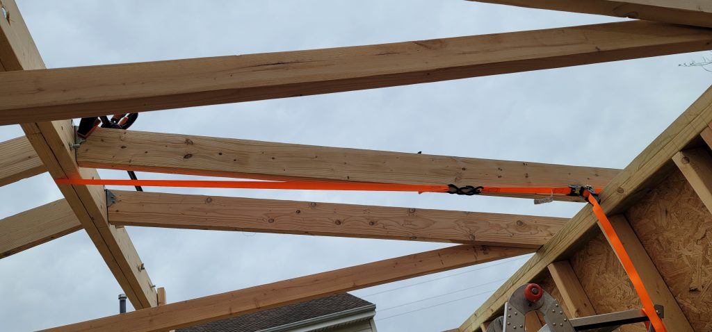 Pulling in ridge beam in line with wall using a ratchet strap